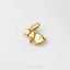 A small gold-colored rabbit ear or earring is shown against a white background.
