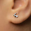 A close-up view of a person's ear with a small silver earring featuring a rabbit design.