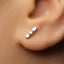 A close-up of a person's ear with a small, silver earring in the earlobe.