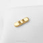 A gold-colored metal object resembling a skateboard is placed on a white surface.