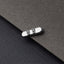 A silver-colored metal object resembling a skateboard or similar wheeled device is placed on a dark grey surface.
