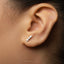 A close-up of a person's ear with a small, silver earring in the earlobe.