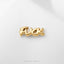 A gold-colored metal object with the word "FUCK" written on it, placed on a white surface.