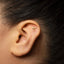 A close-up of a person's ear with a small gold earring in the earlobe.