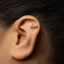 A gold earring with the word " fuck" engraved on it is shown in the image.