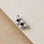 A silver earring with a curved design is resting on a textured surface.