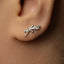 A close-up of a person's ear with a silver earring featuring a leaf design.