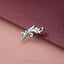 A silver decorative piece with an ornate, leaf-like design rests on a textured purple surface.