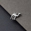 A silver camel-shaped earring is resting on a textured gray surface.