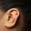 A close-up of a person's ear with a small gold earring in the earlobe.