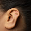 A close-up of a person's ear with a small gold earring in the earlobe.