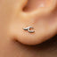 A close-up view of a person's ear with a small silver earring in the earlobe.