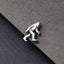 A silver-colored metal object resembling a small, metallic creature or figure is placed on a textured gray surface.