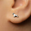 A close-up of a person's ear with a small silver earring featuring a small dog-like figure.