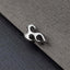 A silver-colored metal object resembling a flame or flame-like shape is resting on a textured gray surface.