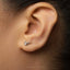 a close-up view of a person's ear with a small silver earring in the earlobe.