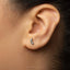 A close-up of a person's ear with a small, silver earring in the earlobe.