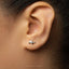 A close-up view of a person's ear, showing a small silver earring with a turtle design.