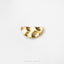 A shiny gold-colored earring with a unique, textured design sits on a plain white background.