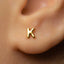A close-up of a person's ear with a small gold letter K earring.