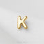 A single, shiny gold letter 'K' is prominently displayed against a white background.