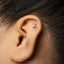 A close-up of a person's ear with a small letter "K" stud in it.