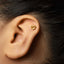 A gold heart-shaped earring is visible in the person's ear.