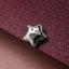 A shiny silver star-shaped object rests on a textured purple surface.