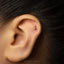 A gold earring with the number 1 on it is visible in the image.