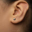 A close-up of a person's ear with a small silver star-shaped earring in the earlobe.