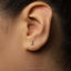 A close-up of a person's ear with a small silver earring featuring the number 1 on it.