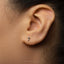 A close-up of a person's ear with a small silver earring featuring the number 7.
