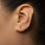A close-up of a person's ear with a small gold number 2 earring.