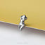 A silver earring in the shape of a female figure is shown against a yellow background.