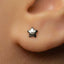 A close-up of a person's ear with a small star-shaped earring in the earlobe.