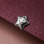 A silver star-shaped charm with a smiley face is resting on a textured purple surface.