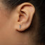 A close-up of a person's ear with a small silver earring in the earlobe.