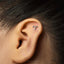 a close-up view of a person's ear with a small silver earring in the earlobe.
