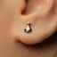 A close-up view of a person's ear with a small silver earring in the earlobe.