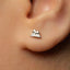 A close-up of a person's ear with a small, diamond-encrusted earring in the earlobe.