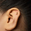 A gold-colored letter "J" stud earring is visible in the person's ear.