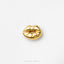 A single, shiny gold-colored object resembling a pair of lips or a mouth, placed against a plain white background.