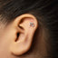 A silver earring with the letter "m" on it is visible in the image.