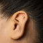 A close-up of a person's ear with a small gold earring in the earlobe.
