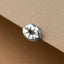 A silver-colored metal object resembling a heart shape is placed on a textured surface.