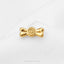 A shiny gold-colored metal object resembling a candy or lollipop is placed on a white surface.