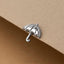 A small silver umbrella charm is placed on a beige surface.