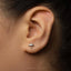 A close-up of a person's ear with a small silver earring featuring an umbrella design.