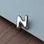 A close-up image of a metallic letter 'N' on a light blue background.