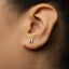 A close-up of a person's ear with a small silver letter 'N' earring.